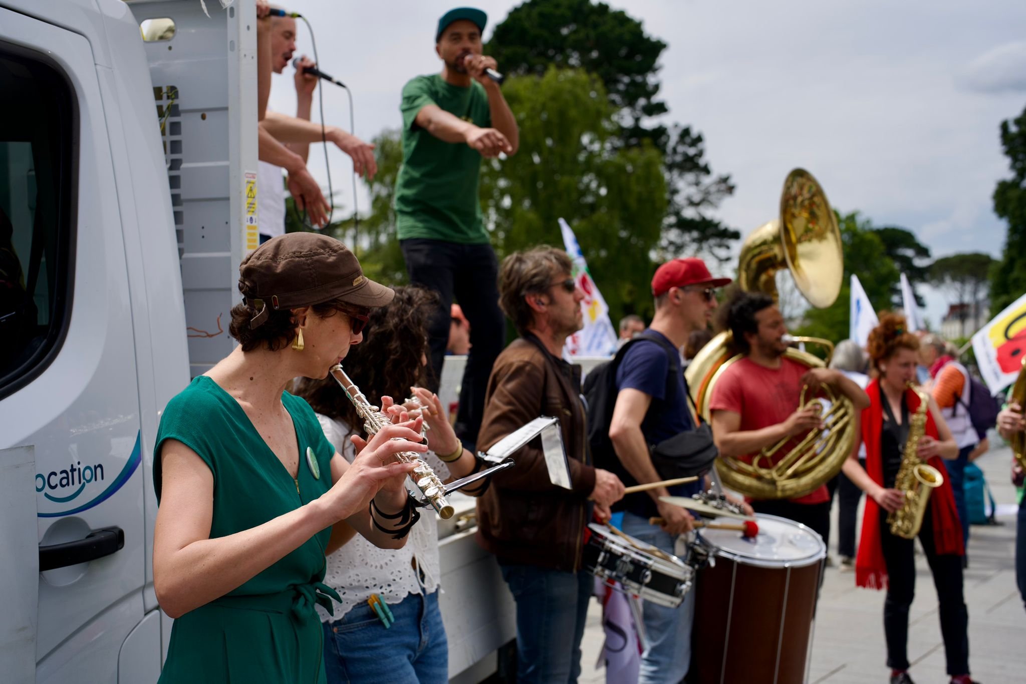 Photo de la fanfare en train de jouer accompagnée du groupe le Dispositif feat. Adam l'ancien installés sur un camion plateau